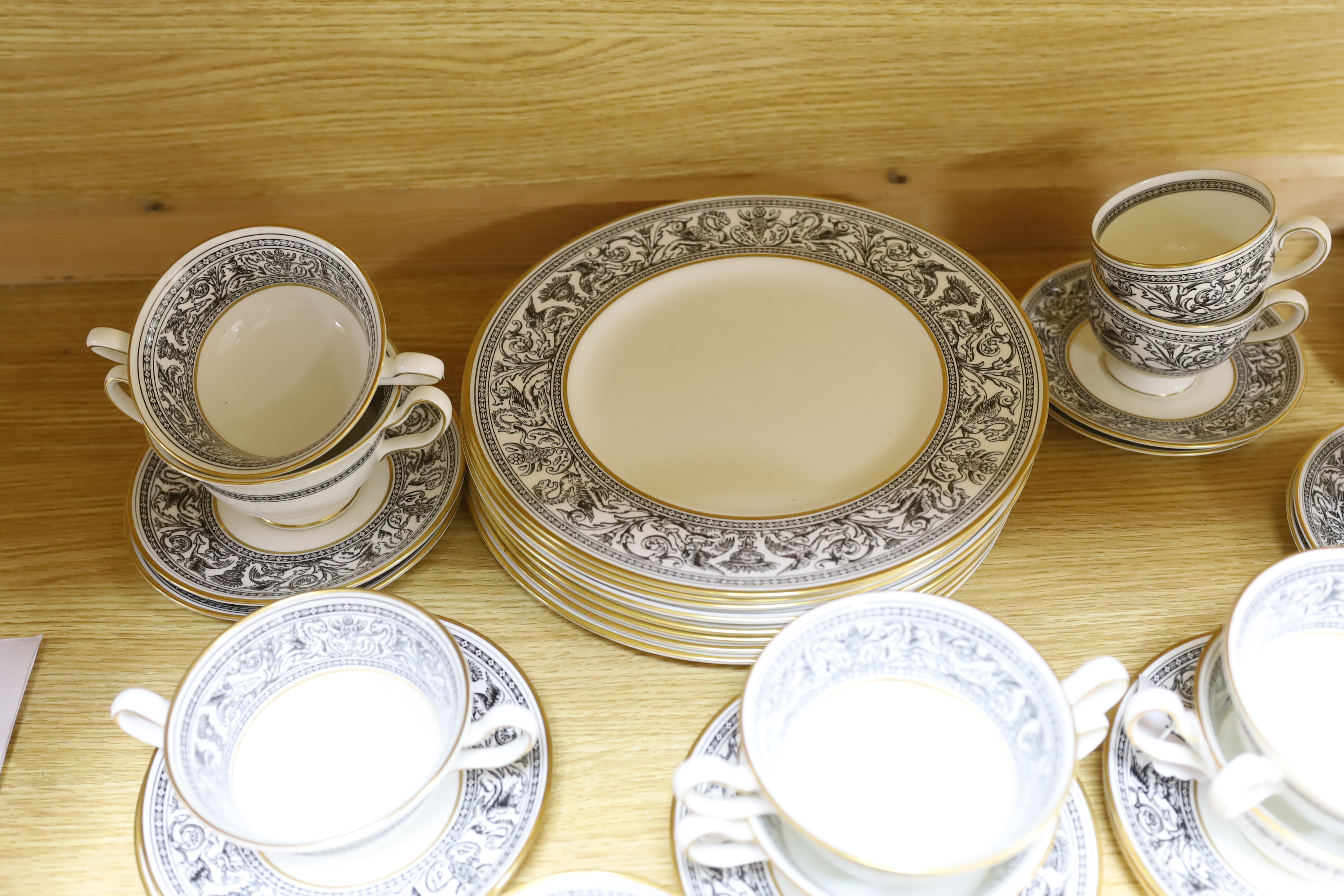 A Wedgwood Florentine part dinner set including twin handled cups, oval platter and dinner plates, largest 34cm wide